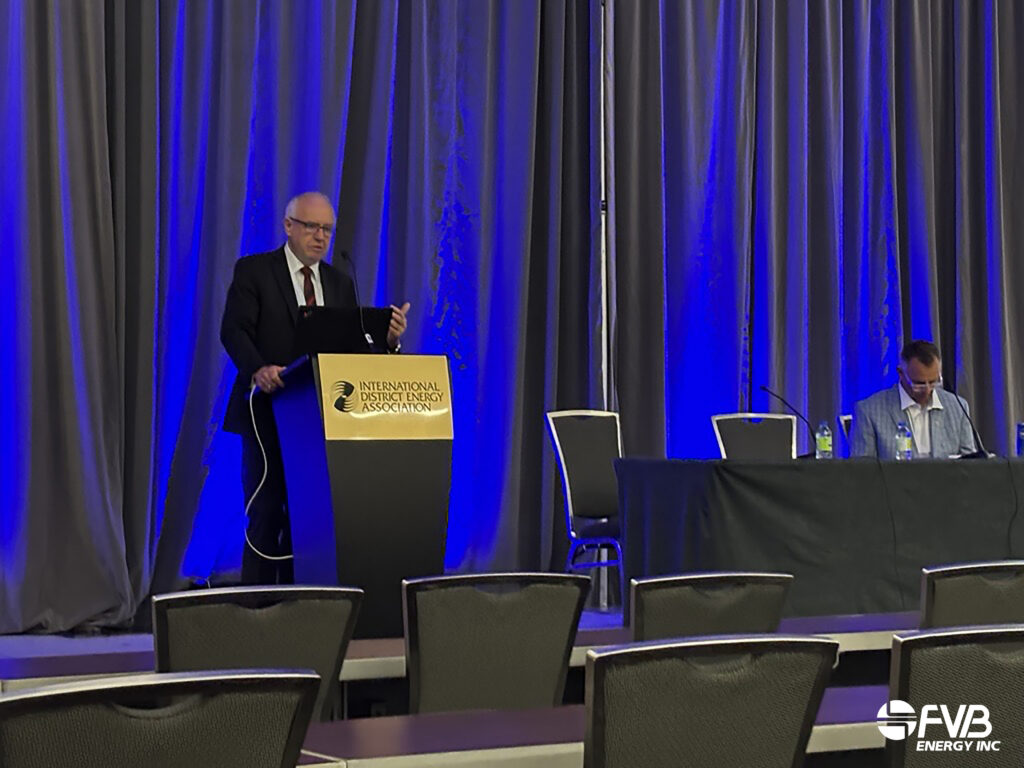 Speaker presenting at IDEA2026 in front of a presentation slide, with panelists seated on stage and attendees in the audience.