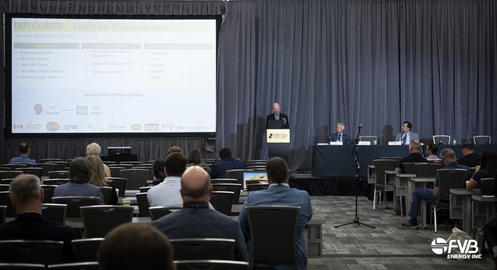 Jim Manson is presenting at IDEA2026 in front of a presentation slide, with panellists seated on stage and attendees in the audience.